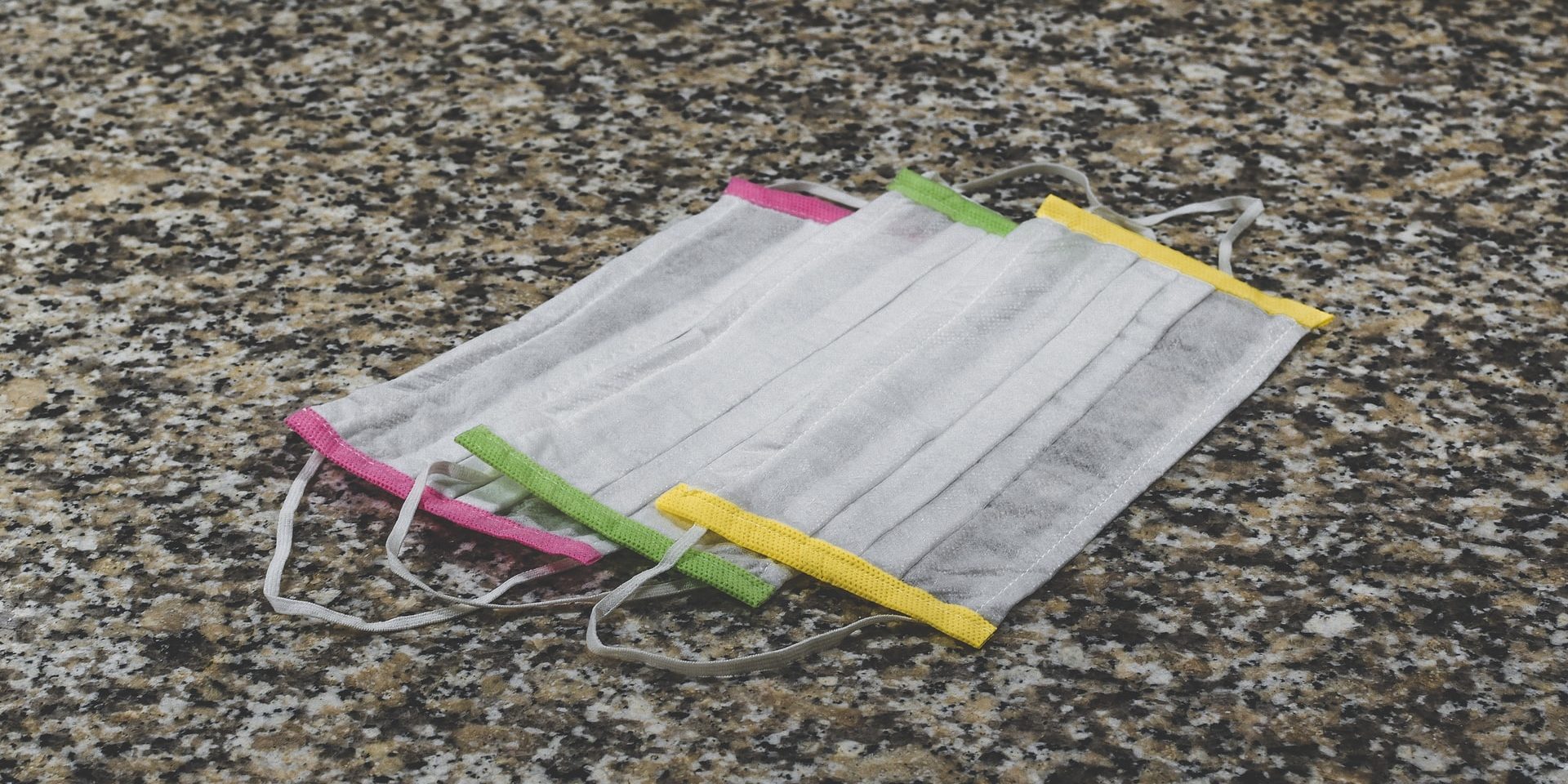 Three colorful surgical masks on a marble surface