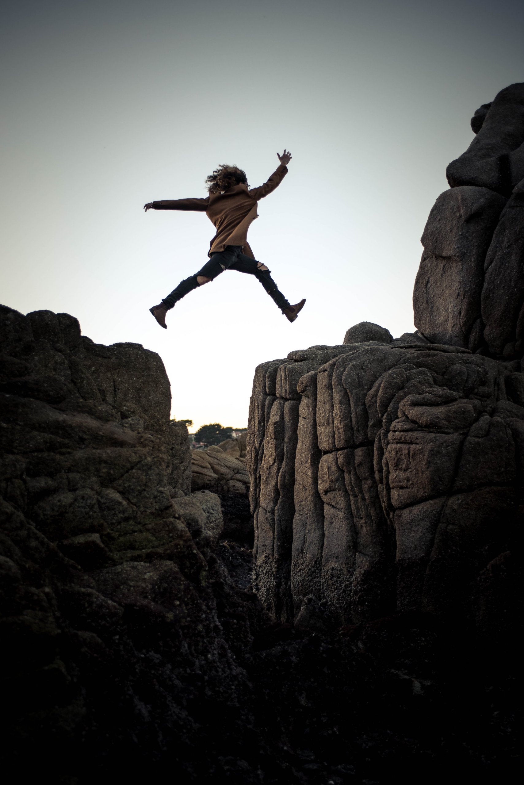 Women jumping over mountain gap