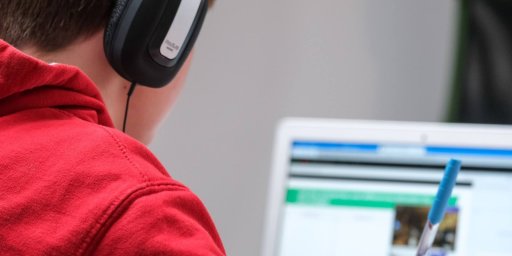 ノートパソコンとヘッドフォンで学校の仕事に取り組んでいる少年