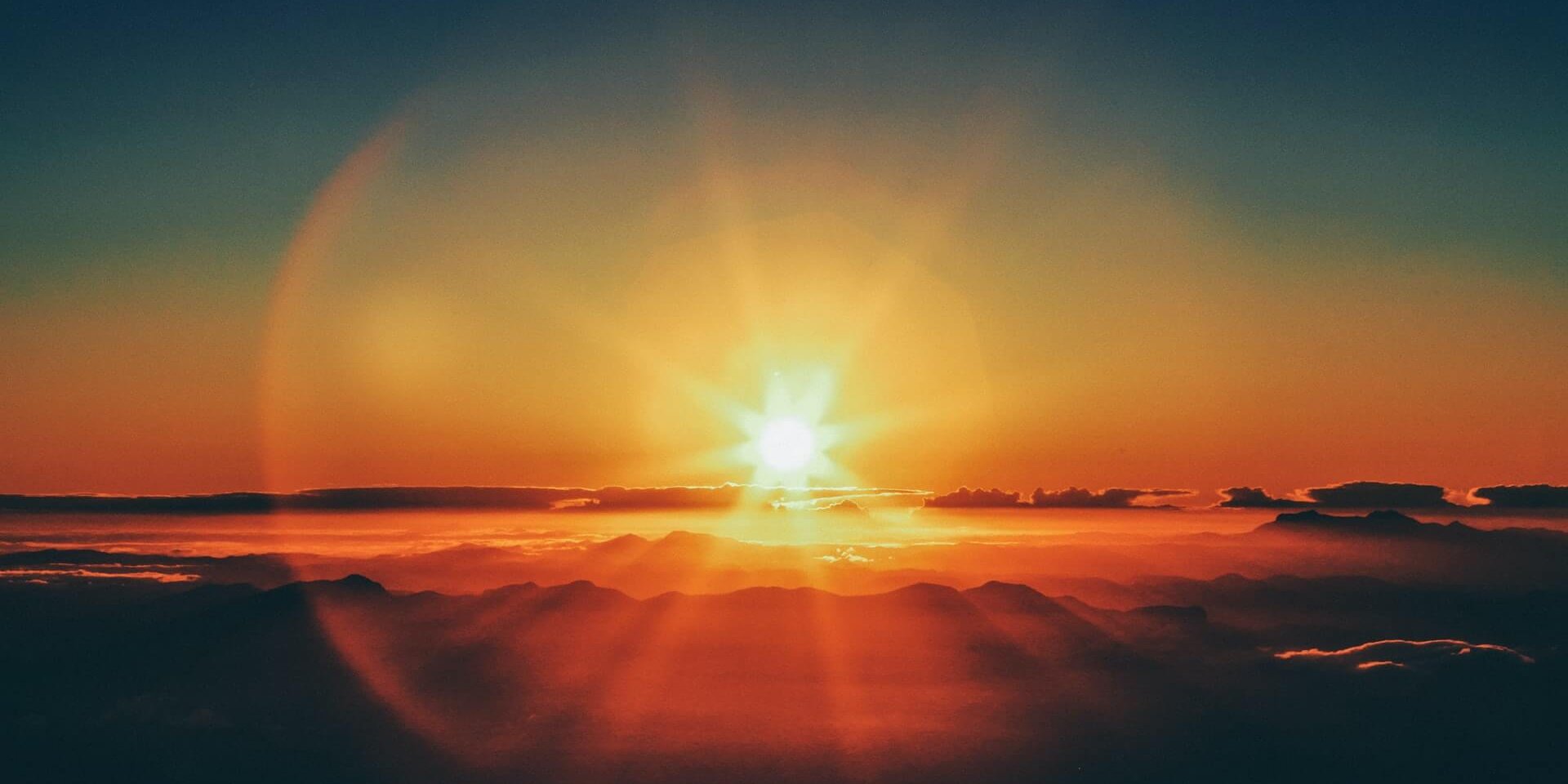 Sun rising over clouds
