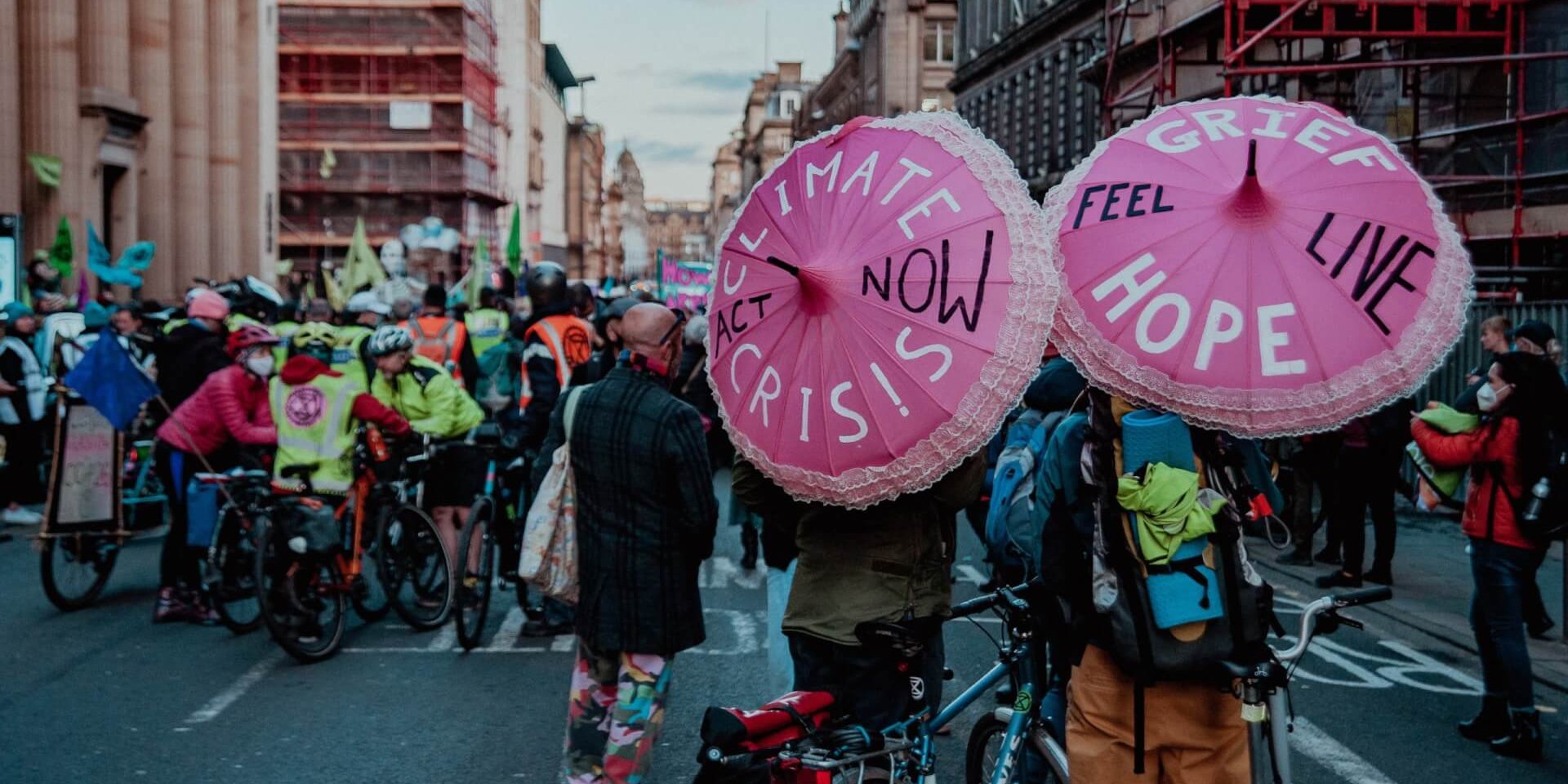 Protestors in Glasgow with painted umbrellas that read "climate crisis- act now"