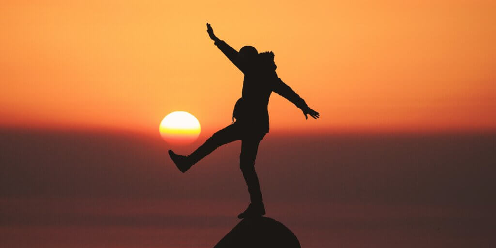 person balancing on a rock at the beach