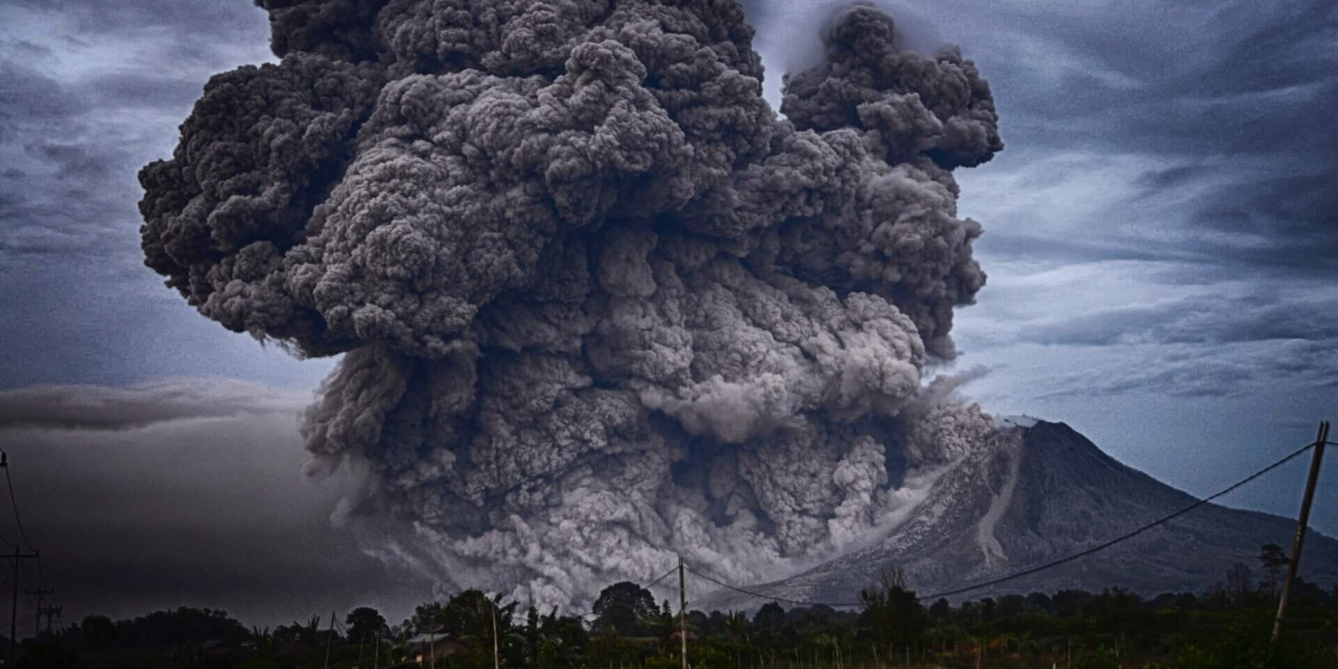 A volcano erupting with clouds of smoke rising from the mountain