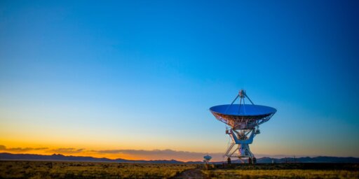 Una antena parabólica gigante con un cielo azul claro durante el anochecer