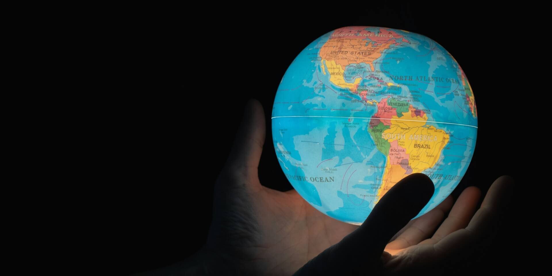 A glowing globe in the hands of a human with dark background