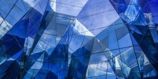 Фотография сине-белого стеклянного здания с абстрактным дизайном.
