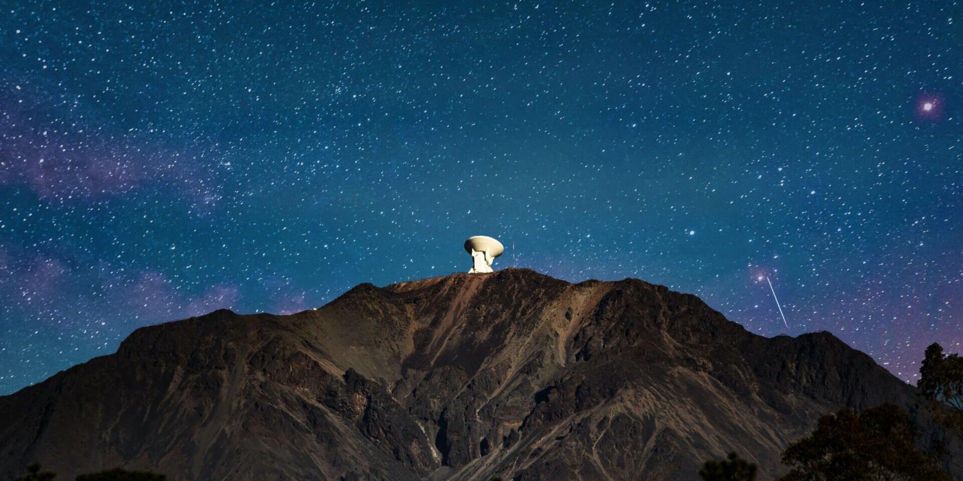 Night sky and a satellite dish on top of a mountain
