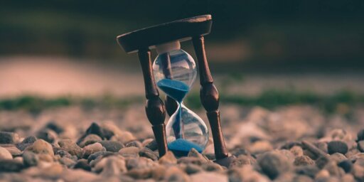 A photo of an hourglass with blue sand inside