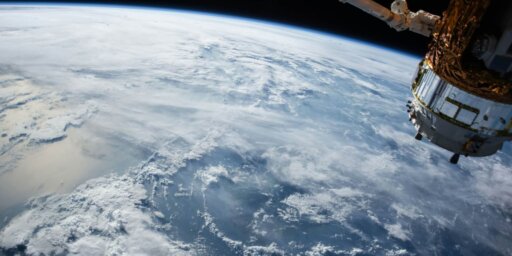 Uma vista do oceano da Terra, das nuvens e de um satélite do espaço sideral
