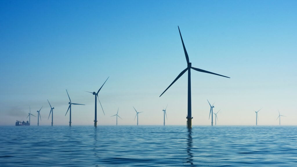 Multiple wind turbines in the ocean with clear blue skies