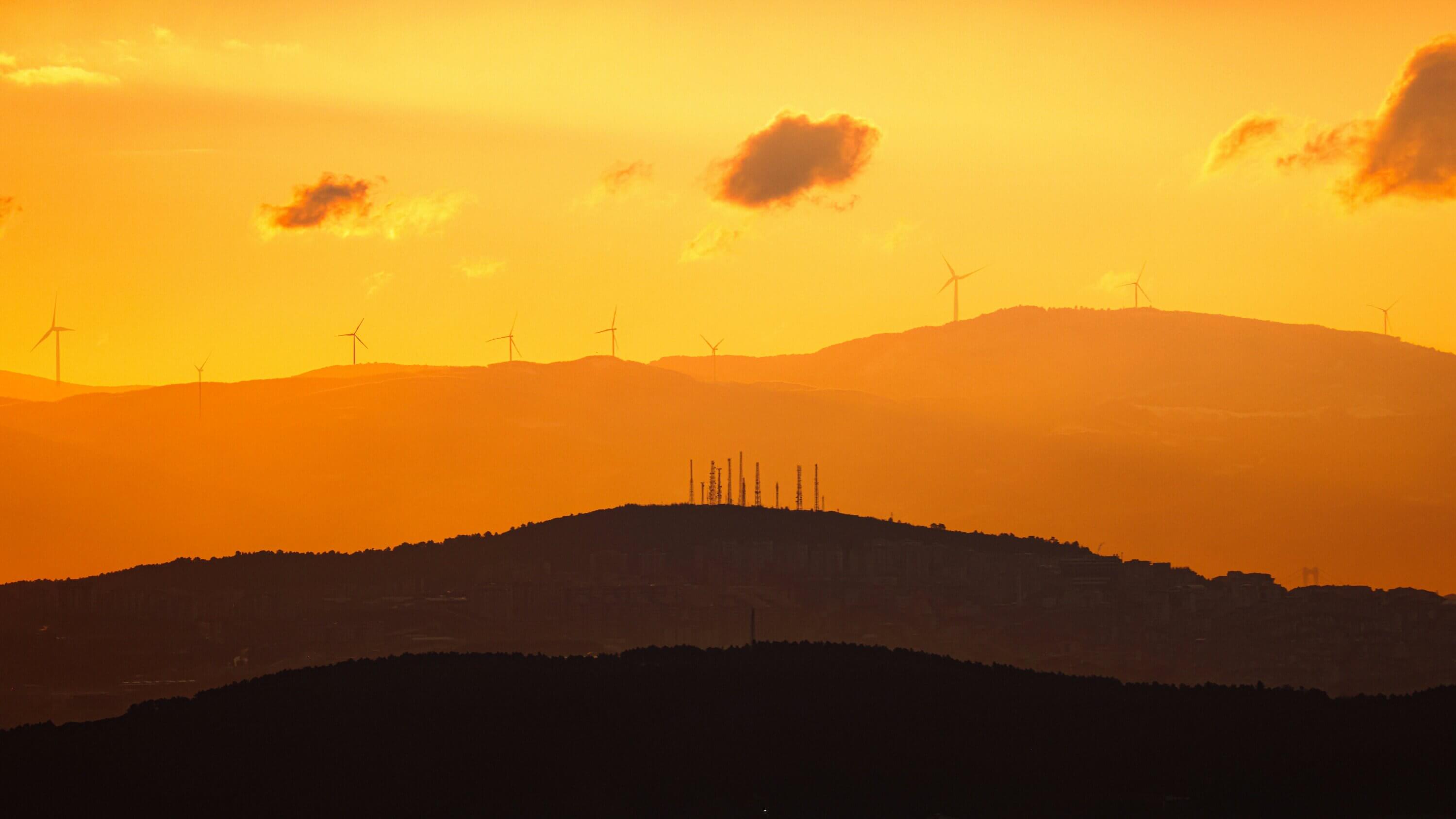 An photo of the hills during sunset with wind turbines and antennas in the distance