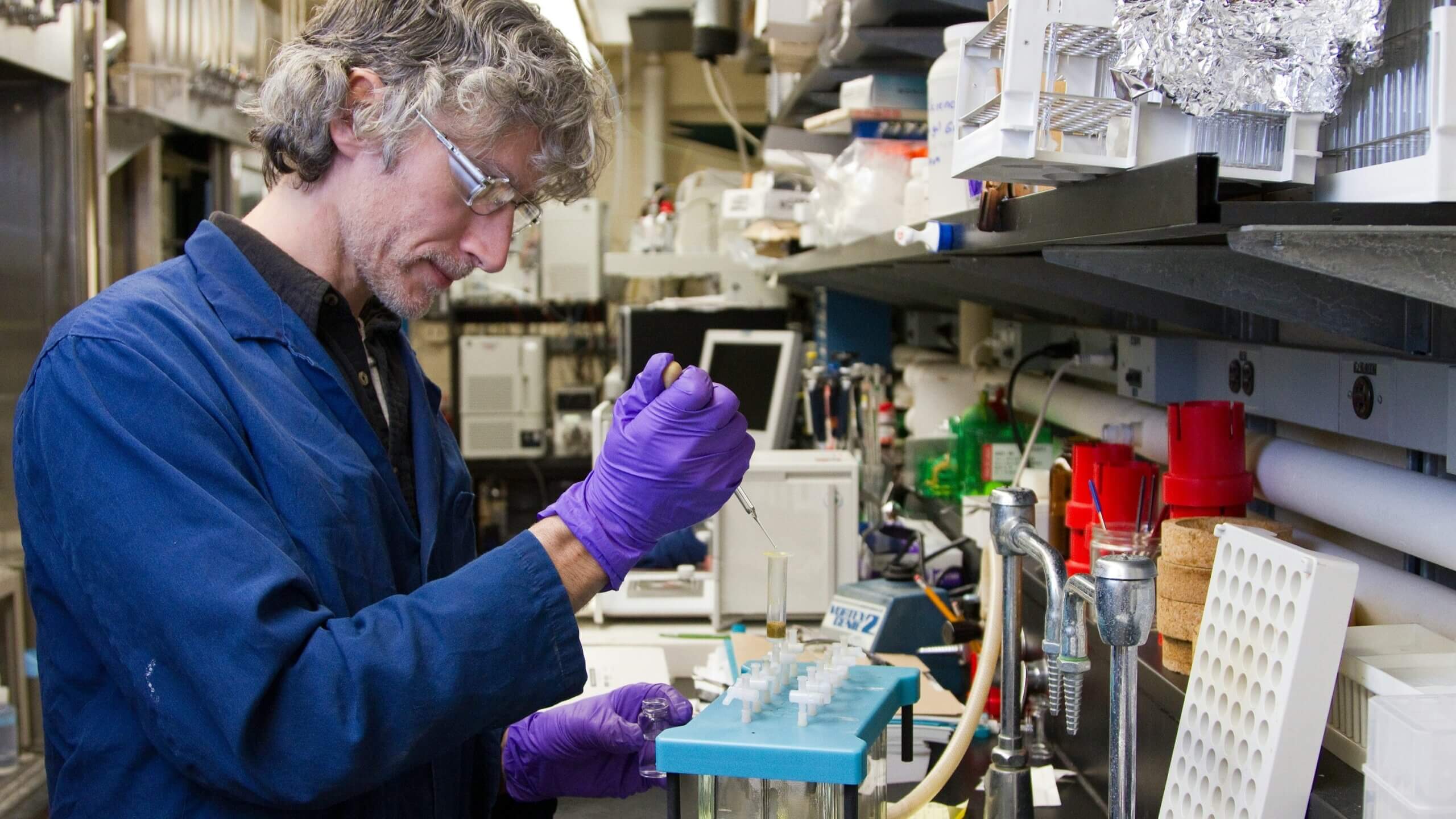 A pharmacist in the laboratory putting a substance in a test tube.