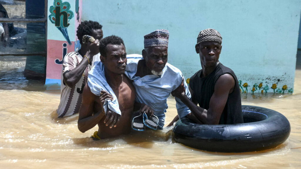 People help an elderly man wade through flood water on Sept. 12 in Maiduguri, Nigeria.