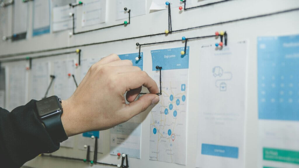 A person's hand on a board designing a structure diagram of a software