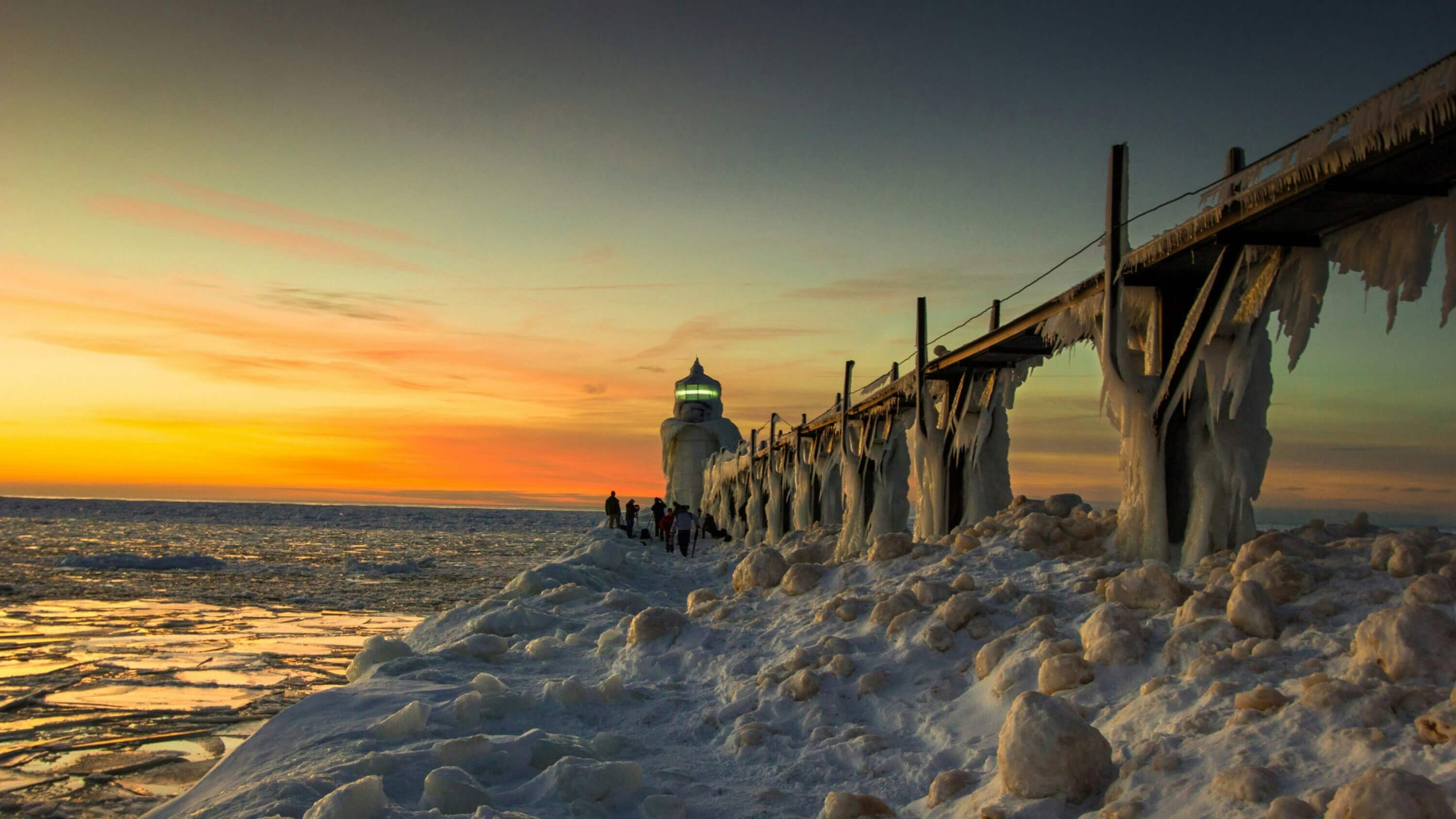 Frozen dock and lighthouse by the sea during sunset