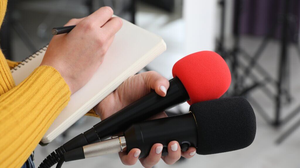 person taking notes with two microphones