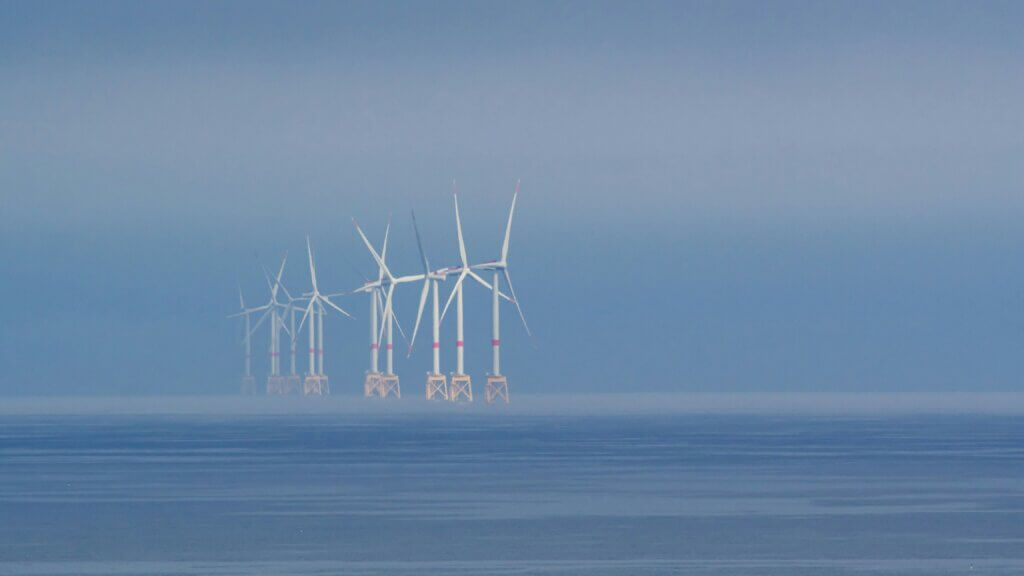 Enmaraj ventoturbinoj staras en la nebula oceano