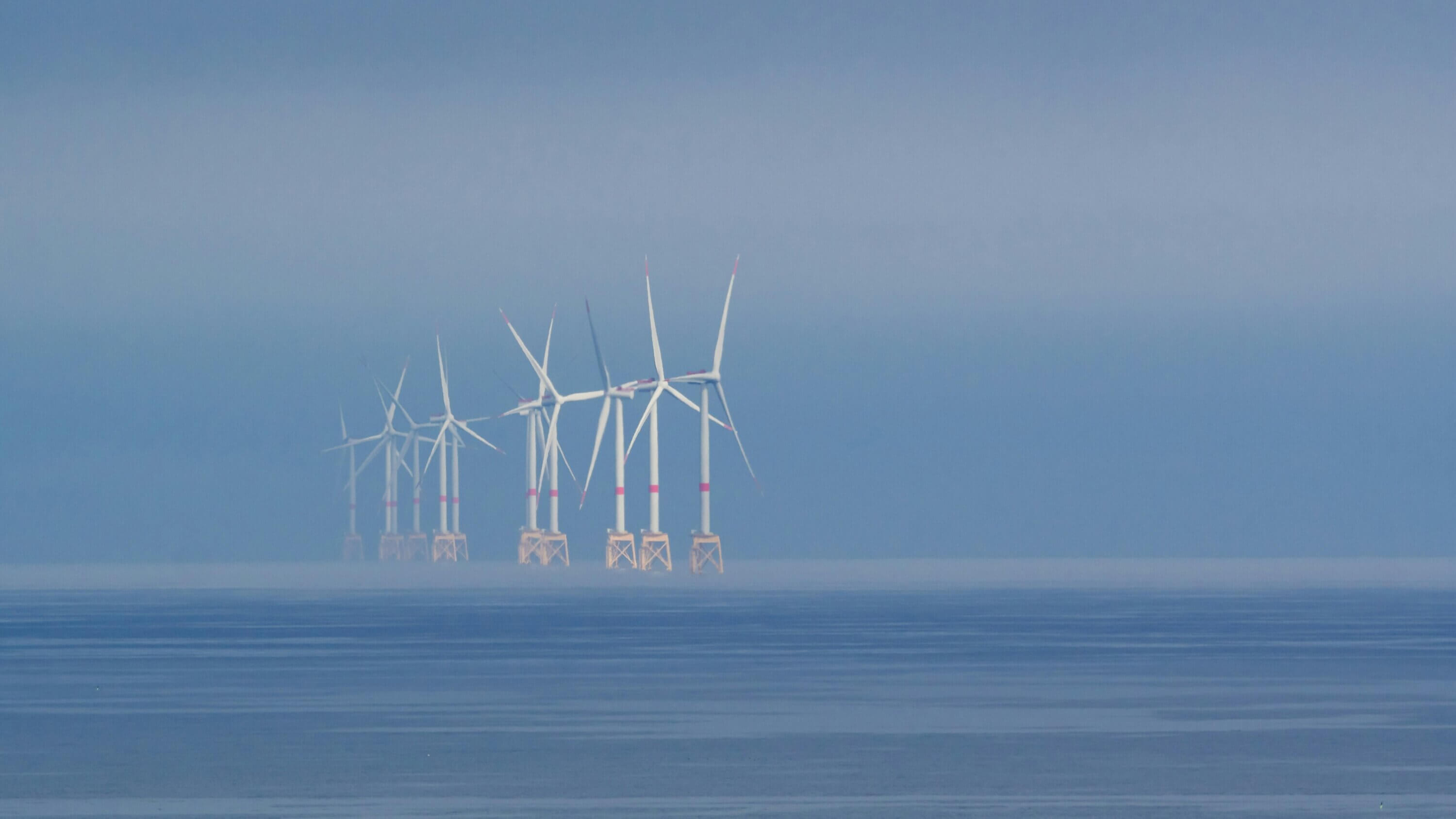 Seasann tuirbíní gaoithe amach ón gcósta san aigéan ceoach