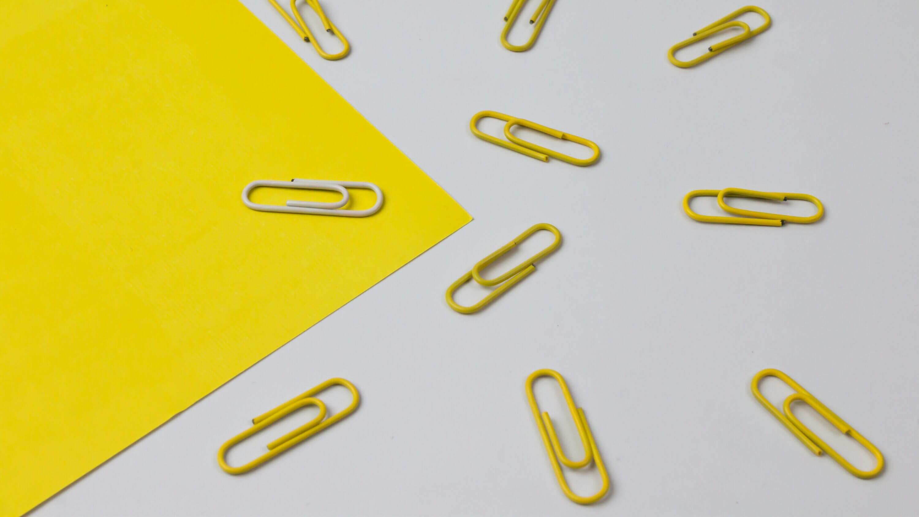Trombones jaunes avec un seul trombone blanc isolé sur fond de papier
